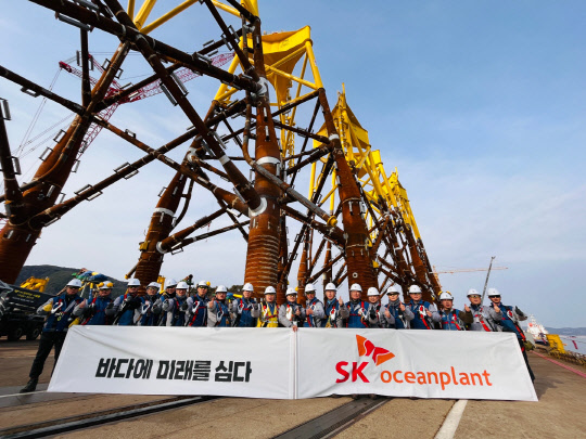 SK오션플랜트 직원들이 수출을 앞둔 해상풍력 재킷 앞에서 기념촬영을 하고 있다.  <사진=SK에코플랜트>